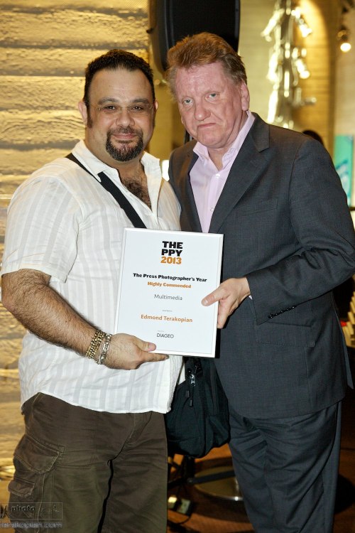 Edmond Terakopian is presented with a Highly Commended certificate (multimedia) for his short film on the RNOH by Ian Wright, Director of Communications at Diageo. Press Photographers' Year (PPY) exhibition private view and award ceremony, National Theatre, South Bank, London.  July 15, 2013. Photo: Peter Bishop / 2013
