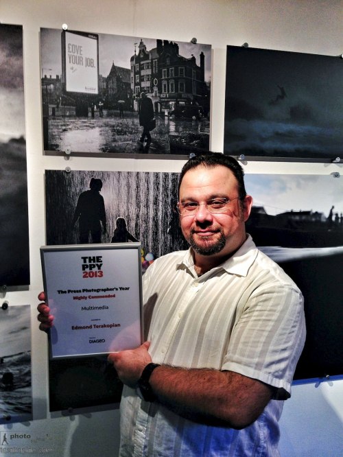Press Photographers' Year (PPY) exhibition private view and award ceremony, National Theatre, South Bank, London.  Edmond Terakopian with a Highly Commended certificate for his RNOH film, standing by his chosen image for the exhibition, Love Your Job.  July 15, 2013. Photo: © / 2013