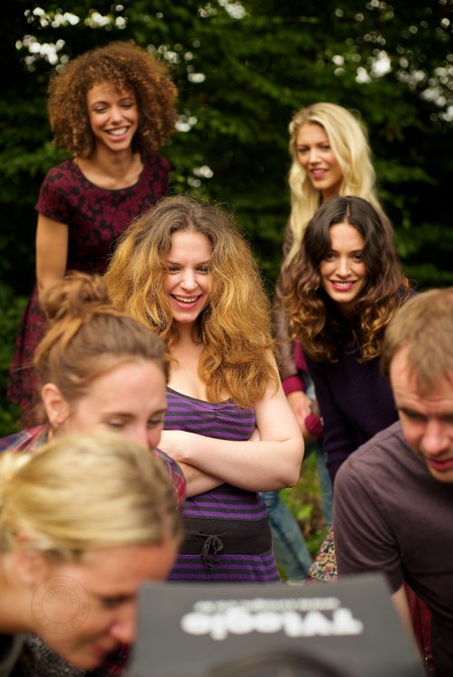 Director Rebecca Gower, surrounded by the models, all have a look at the latest take on a field monitor. New Look behind the scenes shoot of their Autumn / Winter 2013 collection advertising film by Cherry Duck. Walnuts Farm, Old Heathfield, East Sussex, UK. August 22, 2013. Photo: ©Edmond Terakopian