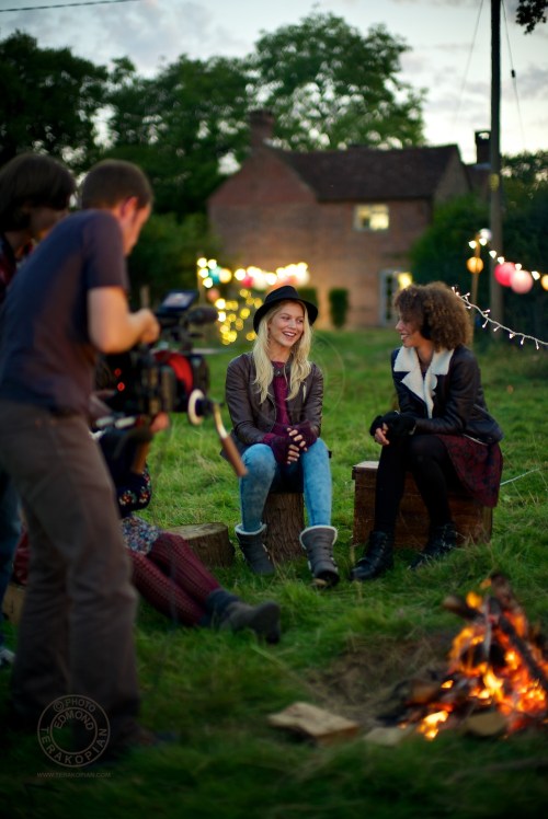 Models (L-R) Lizzie Bowden, Sophie Harries and Leanne Pollock relax by a bonfire. New Look behind the scenes shoot of their Autumn / Winter 2013 collection advertising film by Cherry Duck. Walnuts Farm, Old Heathfield, East Sussex, UK. August 22, 2013. Photo: ©Edmond Terakopian