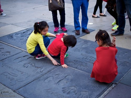 Visitors at the Chinese Theatre forecourt featuring handprints, footprints and signatures of iconic celebrities. The young visitors check out the Harry Potter imprints. Hollywood Boulevard, Hollywood, California. January 16, 2014. Photo: Edmond Terakopian