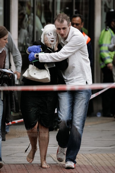 Paul Dadge leads Davinia Turrell (now Davinia Douglass) away from Edgware Road tube station after a suicide bomb attack in which she suffered burn injuries, resulting in the need for a face mask. The bomber blew himself up on a train at the station, killing seven passengers - one of four coordinated attacks on London's public transport system during the morning rush hour. The bombs exploded within 50 seconds of each other on London Underground trains, and the fourth bomb occurred on a bus less than an hour later. The explosions resulted in some 56 deaths (including those of the four bombers) and 700 injuries. Surveillance video footage showed that the four men had been working together. Intelligence services have claimed links between the bombers and al-Qaeda. Edgware Road underground station, London, United Kingdom. July 07, 2005. Photo: Edmond Terakopian